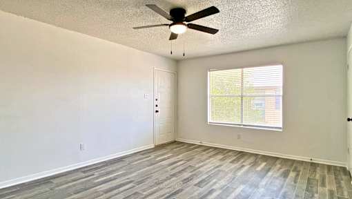 A room with a ceiling fan and a window with blinds.