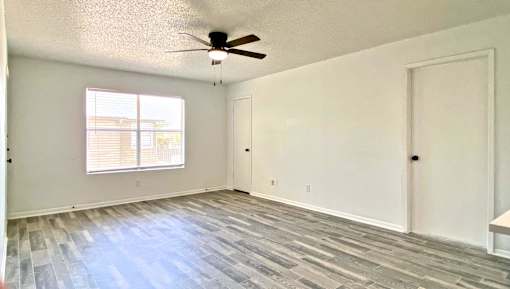 A room with a ceiling fan and a window with blinds.