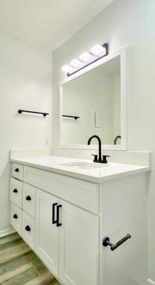A white bathroom vanity with a sink and mirror.