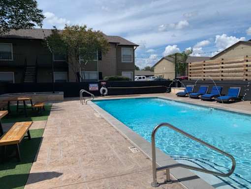 A pool with a metal ladder and a bench outside a building.