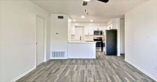 A spacious kitchen with a bar counter and a ceiling fan.
