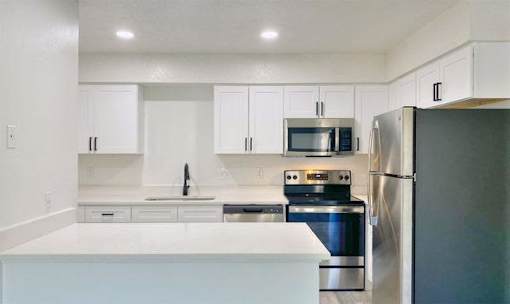 A modern kitchen with stainless steel appliances and white cabinets.