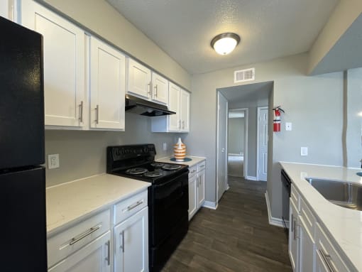 a kitchen with white cabinets and black appliances  at The Alara, Houston, TX