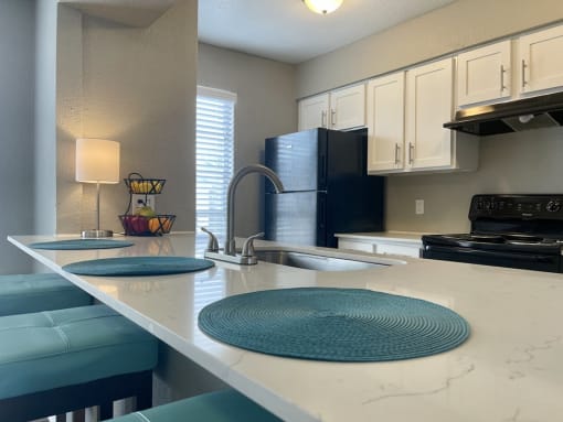 a kitchen with white cabinets and black appliances  at The Alara, Houston