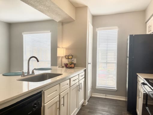 a kitchen with white cabinets and black appliances  at The Alara, Houston, TX, 77060