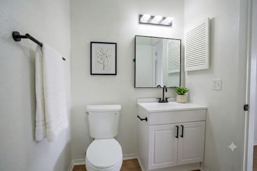 A white toilet sits next to a white sink in a small bathroom.