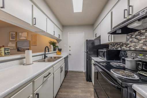 A kitchen with a black stove top oven and a white counter top.