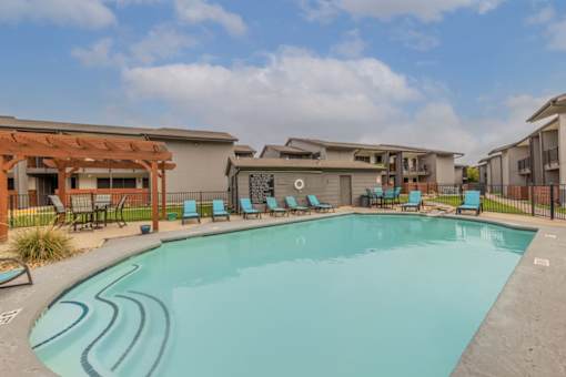 A swimming pool surrounded by lounge chairs and buildings.