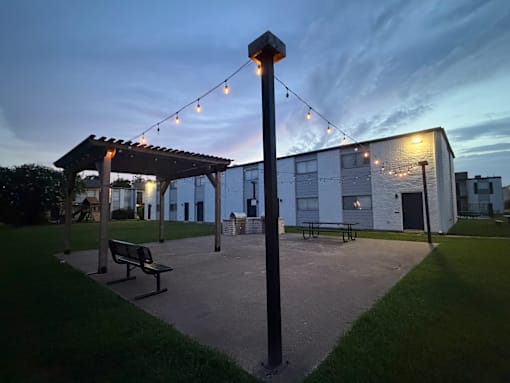 A park with a bench and a pole with lights.