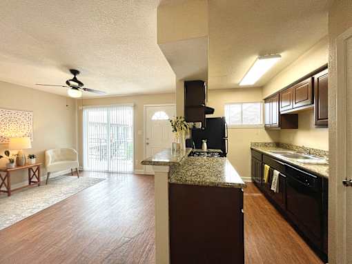 A kitchen with dark wood cabinets and a marble countertop.