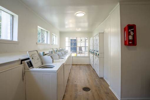 A laundry room with a washer and dryer and a red fire extinguisher on the wall.