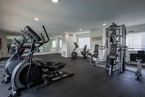 A spacious gym with a variety of equipment including a treadmill, weights, and a bench press.