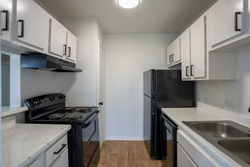 A kitchen with black appliances and white cabinets.