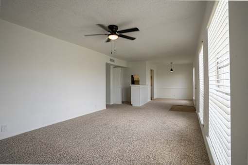 A room with a ceiling fan and carpeted floor.