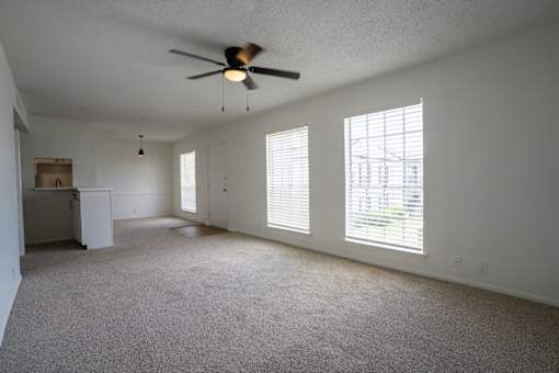 A room with a ceiling fan and carpeted floor.