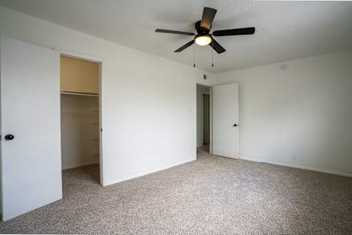 A room with a ceiling fan and carpeted floor.