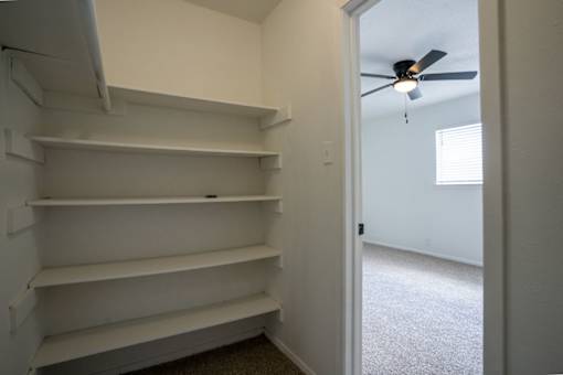 Empty white shelves in a room with a ceiling fan.