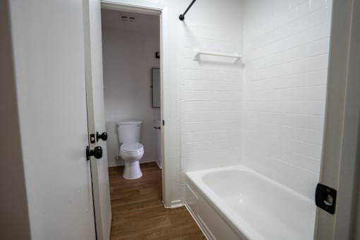 A white bathroom with a toilet and a bathtub.