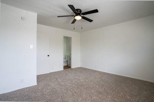 A room with a ceiling fan and carpeted floor.