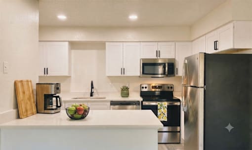 A kitchen with white cabinets and a black refrigerator.