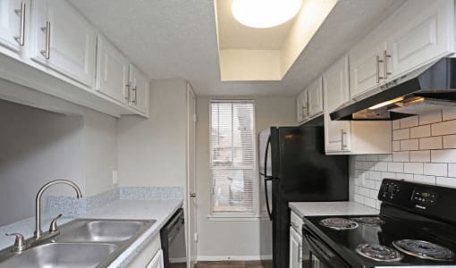 an empty kitchen with black appliances and white cabinets  at 1505 Exchange Apartments, Fort Worth, TX, 76112