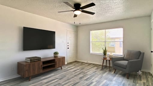 A living room with a television, a chair, and a wooden cabinet.