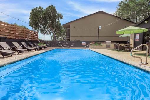 A large blue swimming pool with a wooden deck and sun loungers.