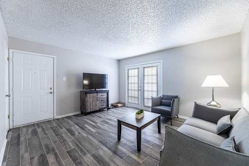 A living room with a grey couch, a wooden coffee table, and a television.