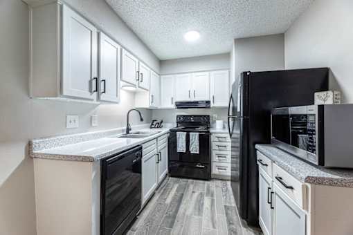 A kitchen with black appliances and white cabinets.