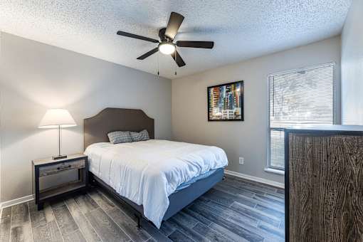 A bedroom with a bed, nightstand, and a ceiling fan.