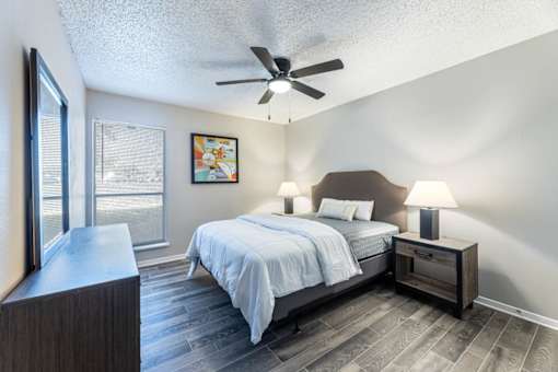 A bedroom with a bed, nightstand, and a ceiling fan.