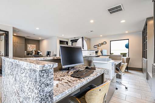 A modern kitchen with a marble island and a computer on it.