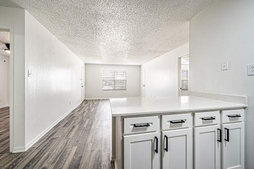 A kitchen with white cabinets and a counter top.