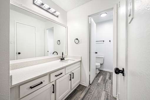A bathroom with a white sink vanity and a white toilet.