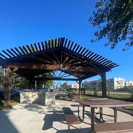 A wooden pergola with a table and chairs underneath it.