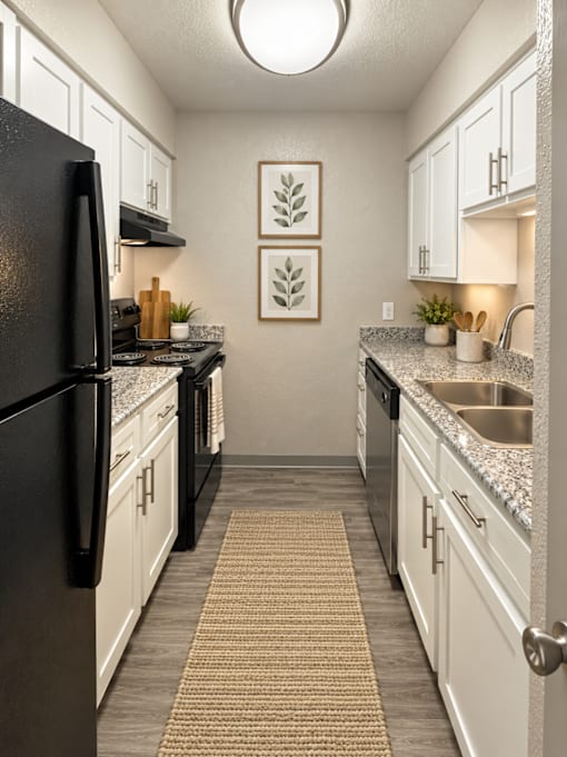 A kitchen with black appliances and white cabinets.