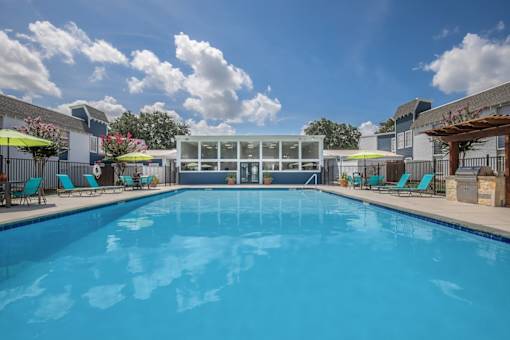 A large swimming pool with lounge chairs and umbrellas.