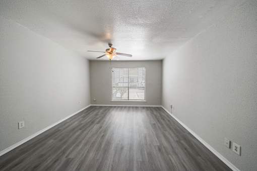 A room with a ceiling fan and wooden flooring.