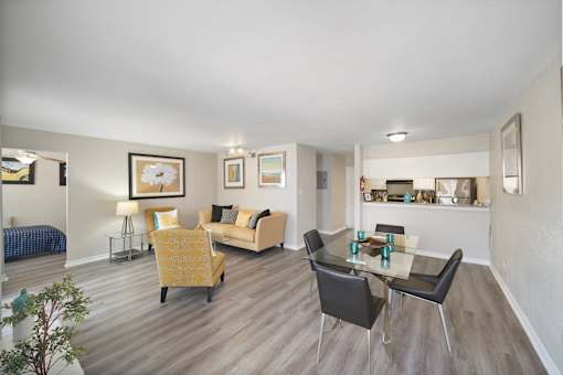 A living room with a yellow chair and a glass table.