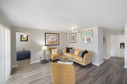 A living room with a yellow chair and a beige couch.