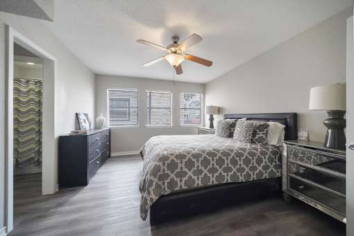 A bedroom with a bed, dresser, and ceiling fan.