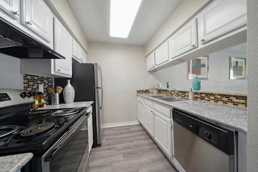 A kitchen with black appliances and white cabinets.