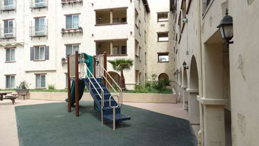A playground with a slide and a bench in front of a building.