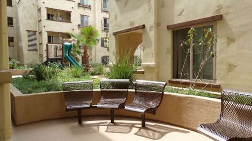 A patio with a bench and a tree.