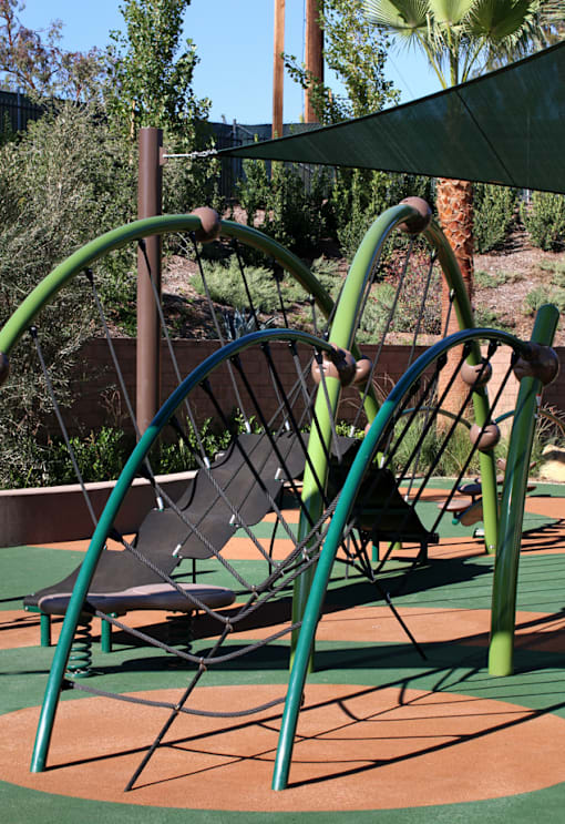 A playground with a green swing set and a brown bench.