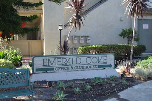 A sign that says Emerald Cove in front of a building.