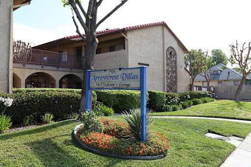 A sign for Arrowcrest Dillas stands in front of a building.