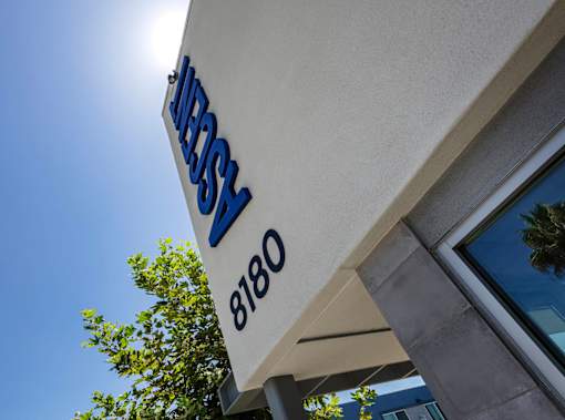 A sign with the word "JEBS" in blue letters above the number "8180" is mounted on a white wall.