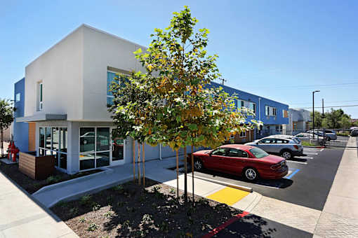 A modern building with a red car parked in front.