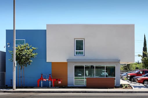 A modern building with a blue and white exterior and a red object in front.